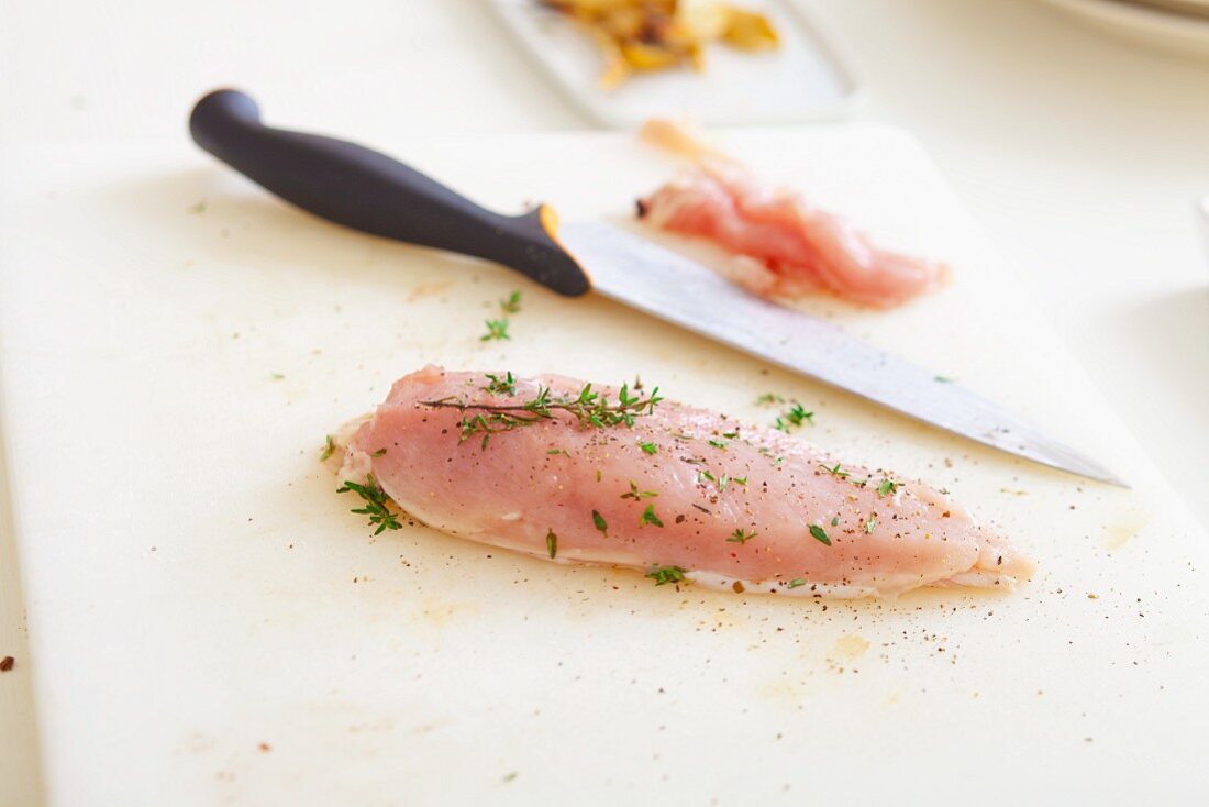 Raw chicken breast sprinkled with thyme