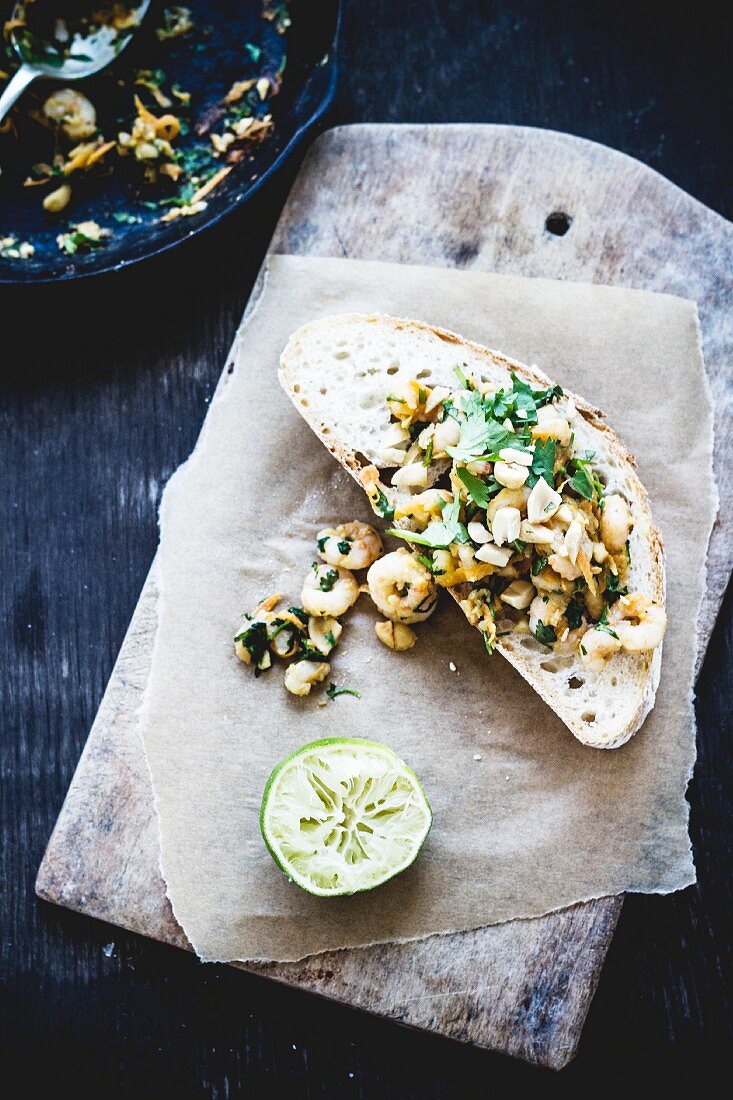 A slice of bread topped with prawns, miso and limes