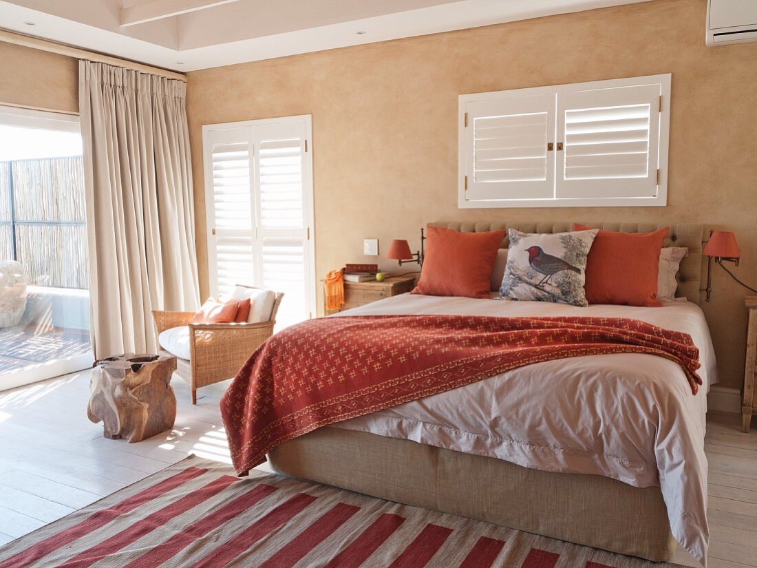 Mediterranes Schlafzimmer mit Doppelbett unter Fenster mit geschlossenen Innenläden und bodenlanger Vorhang an Terrassentür