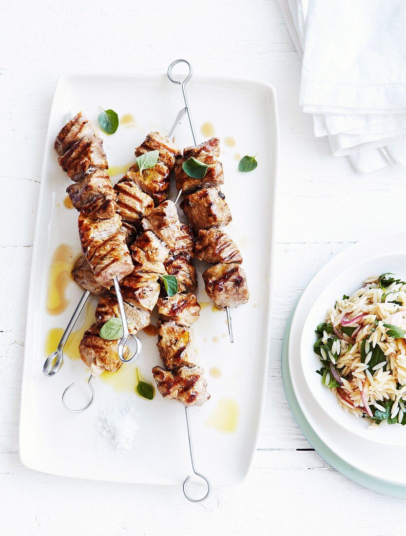 Grilled skewers of pork collar with oregano and orzo salad