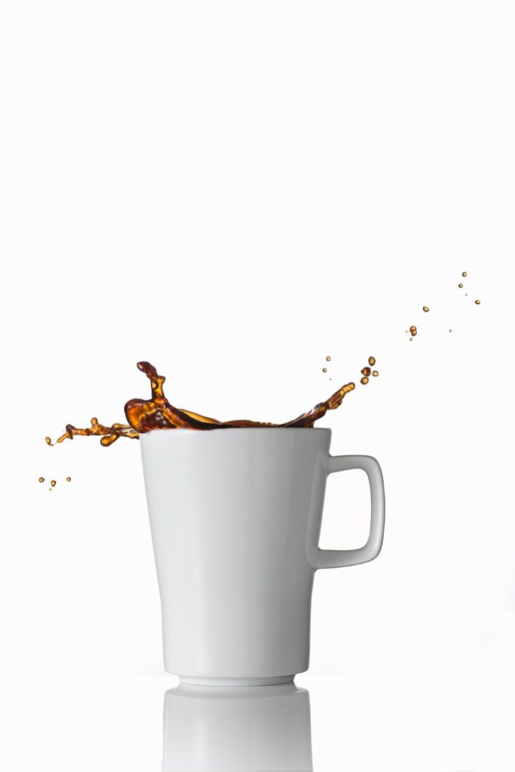Schwarzer Kaffee spritzt aus der Tasse