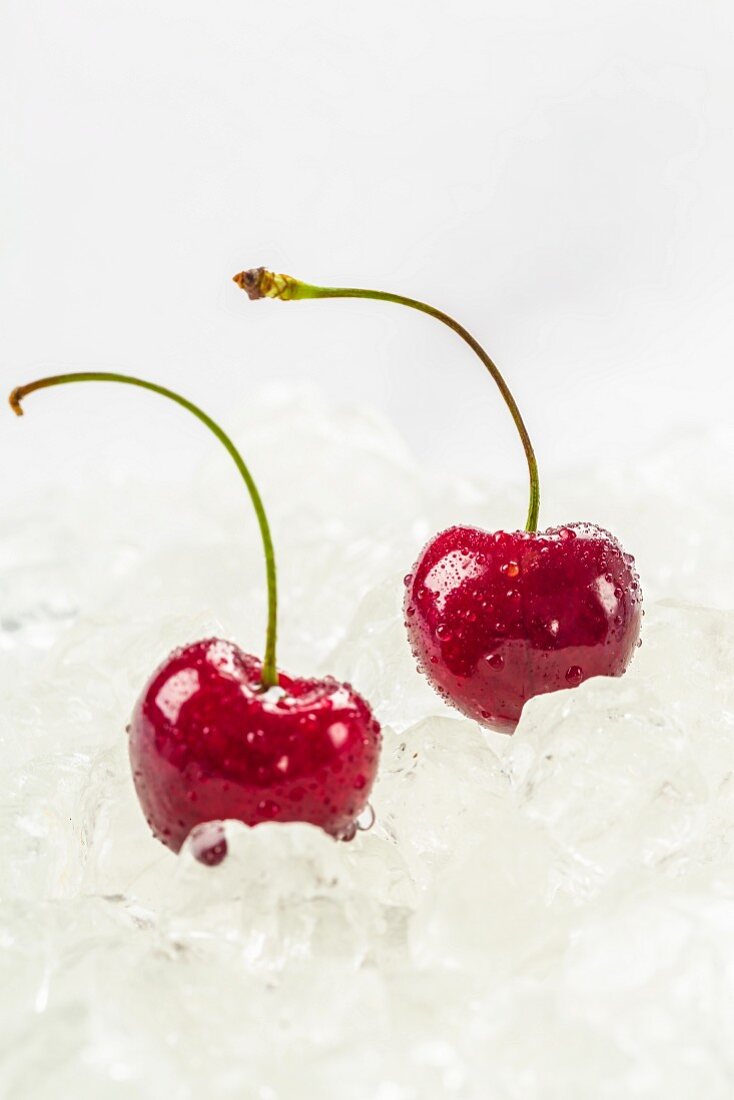 Two cherries with water droplets on ice