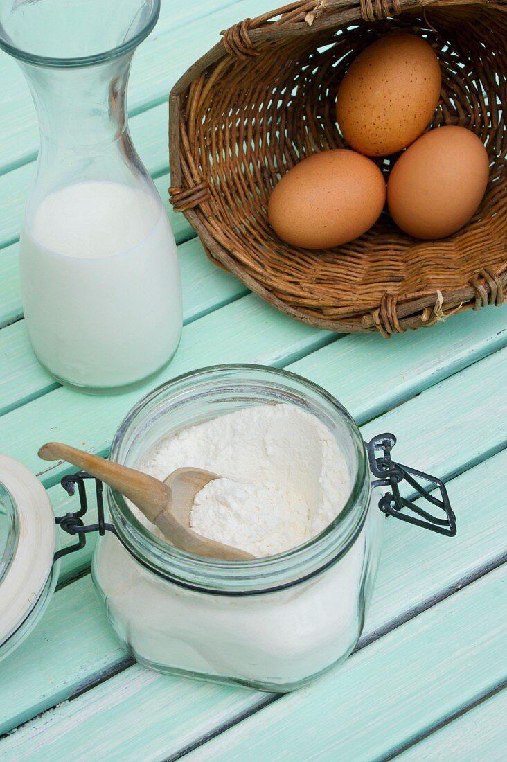 A still life featuring milk, eggs and flour