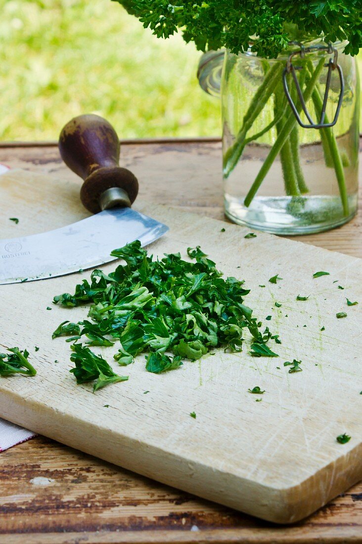 Chopped parsley with a mezzaluna on a wooden board