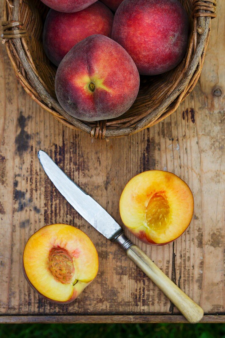 Peach with a basket and a knife on a wooden table