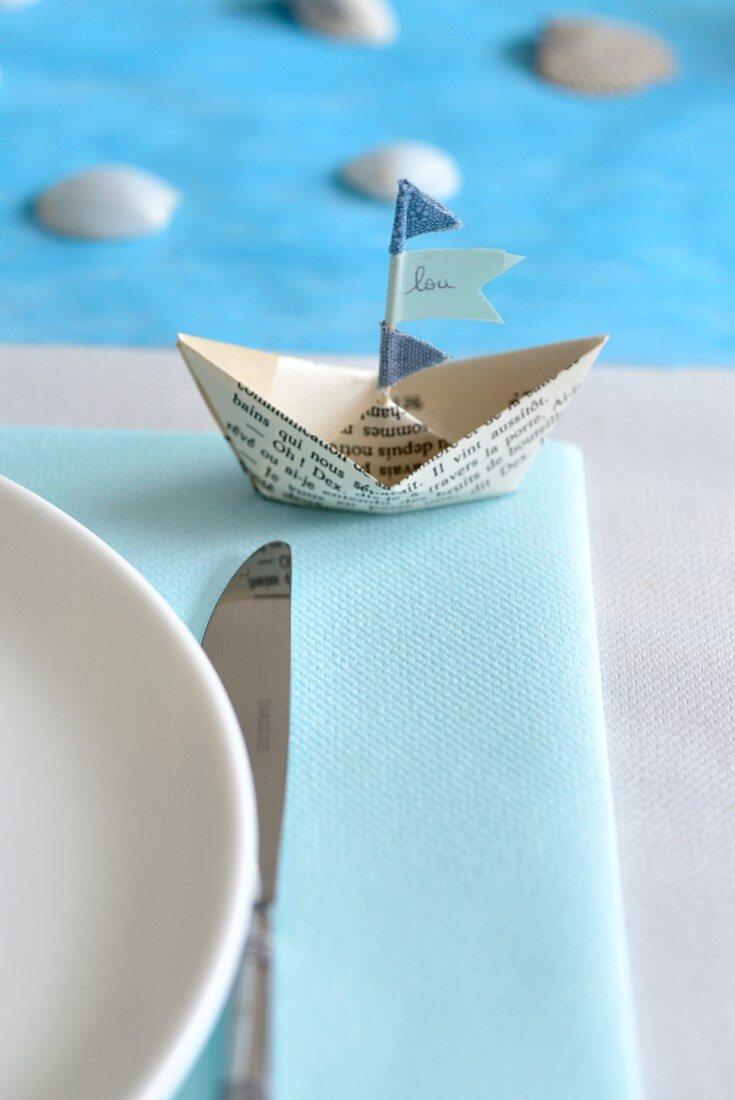 Paper boat with name on flag as place card next to place setting