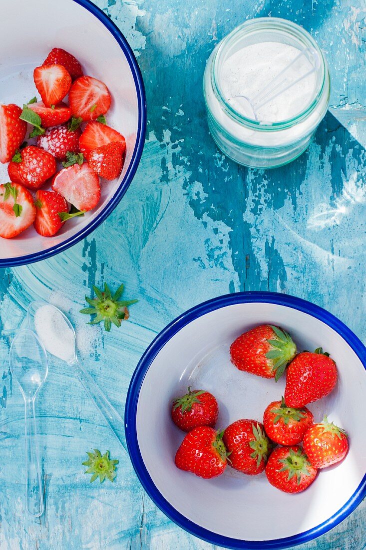 Fresh strawberries in the bowls with sugar