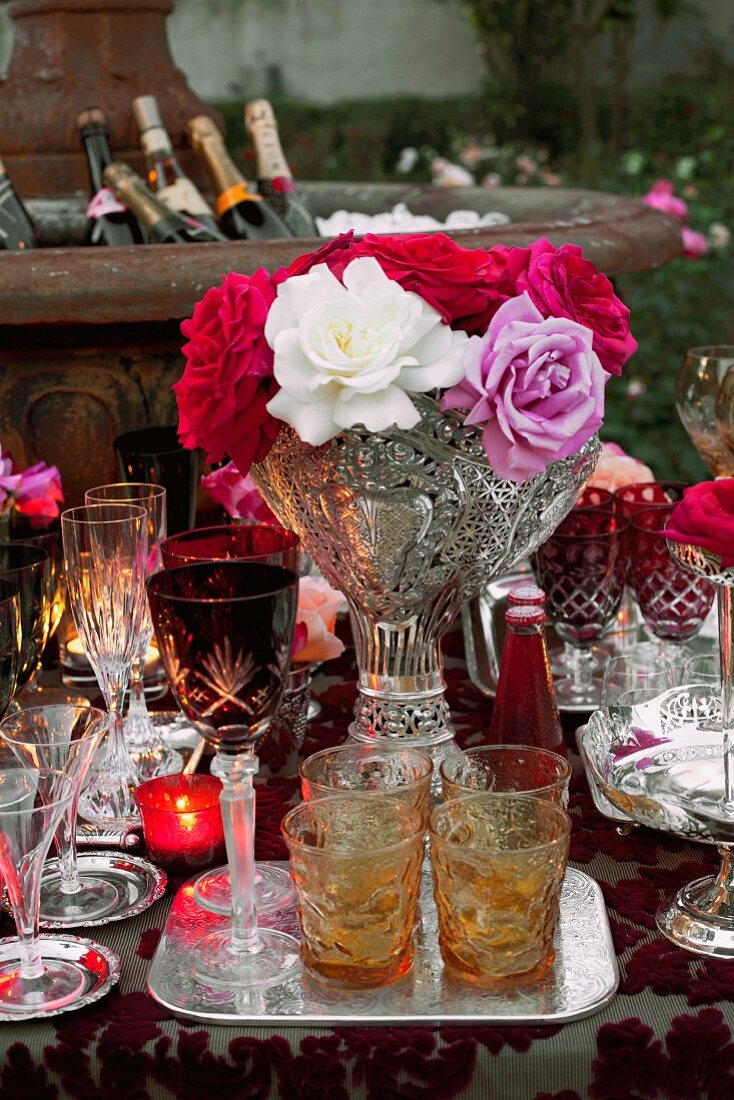 Verschiedene geschliffene Gläser und Blumenstrauß auf Tisch eines Gartenfestes