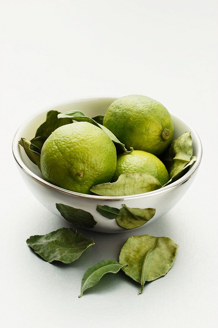 Limes with leaves in a silver bowl