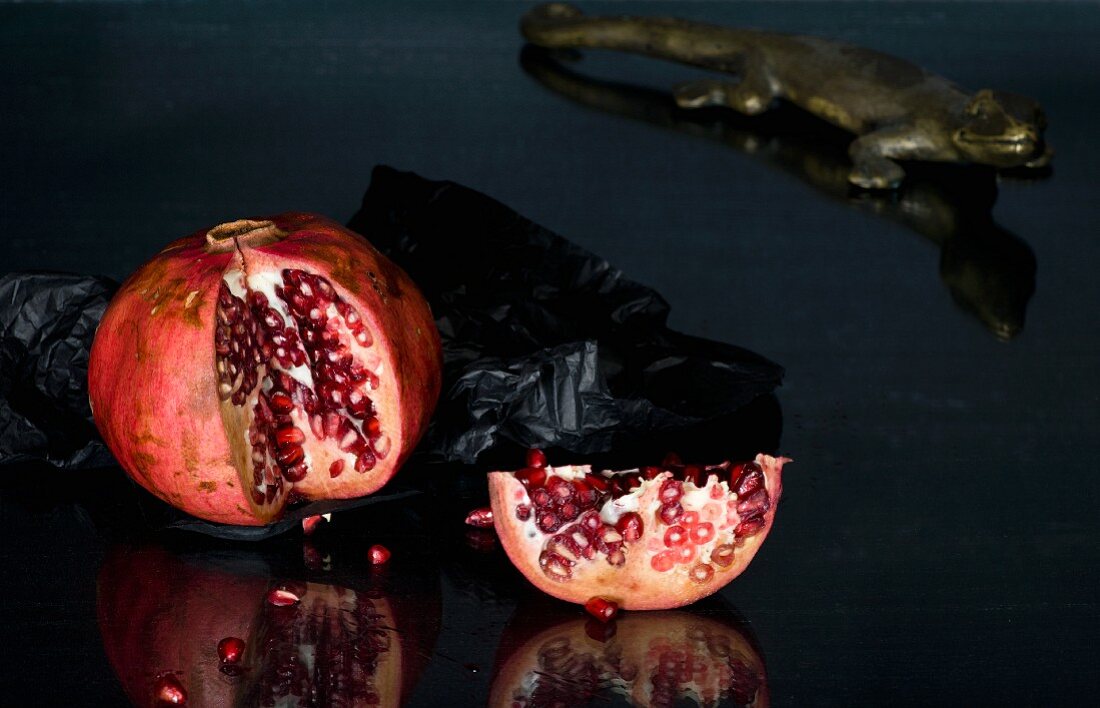 pomegranate with slice removed on a black glass table