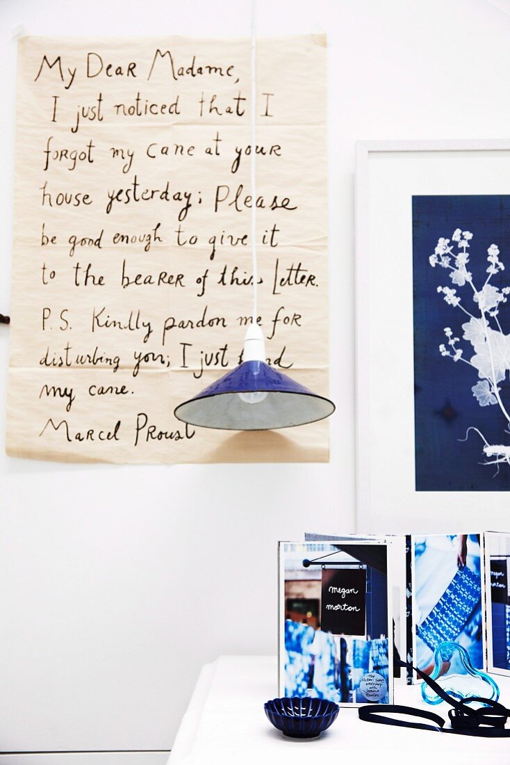 Enlarged, hand-written letter as wall decoration behind blue pendant lamp