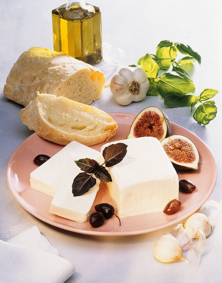 Stück Feta auf Teller mit Feigen, Oliven & Weißbrot