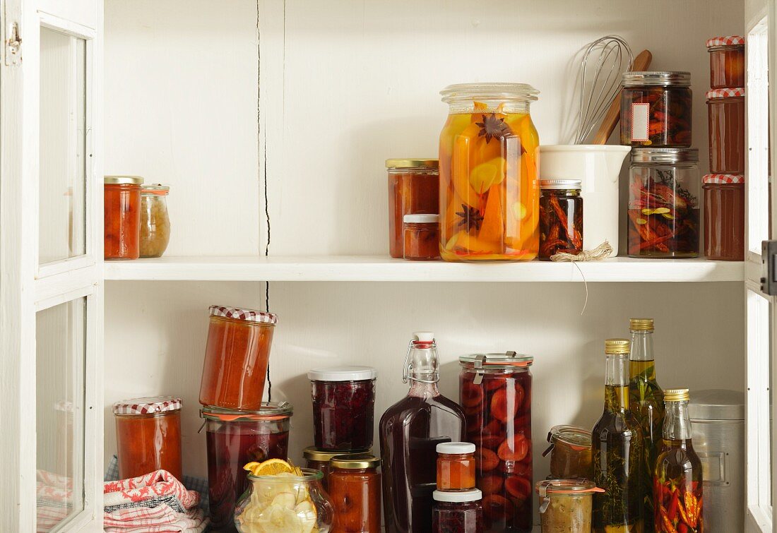 Preserved and pickled fruits in an open storage cupboard