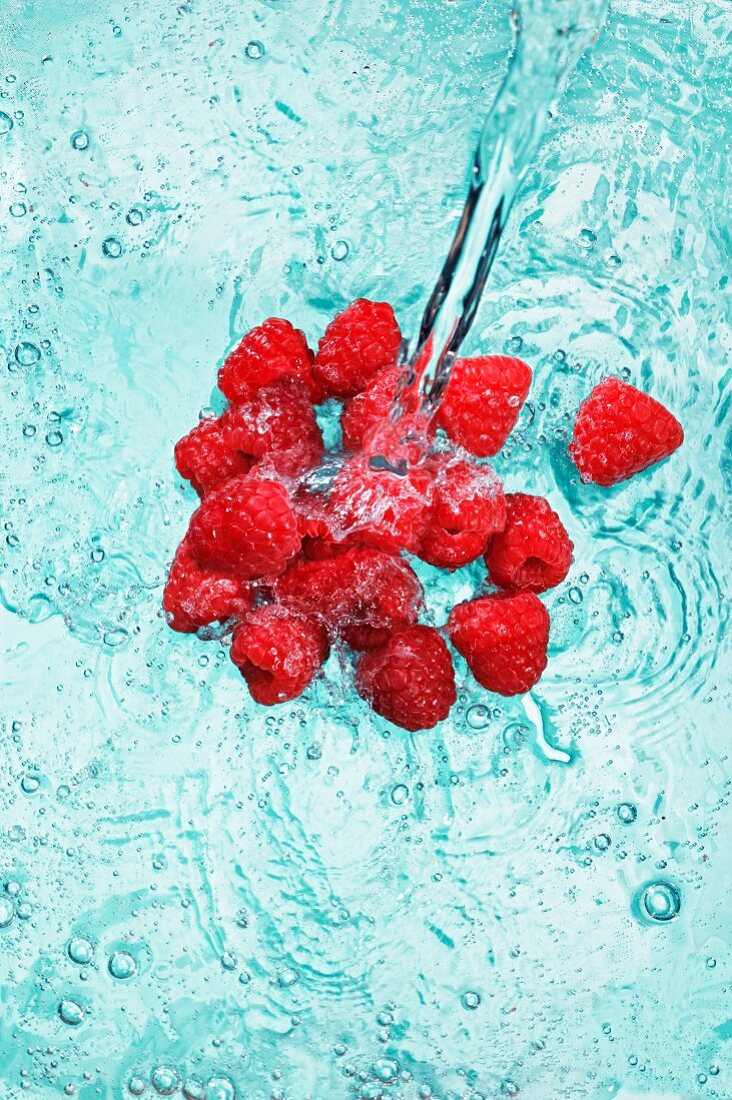 Raspberries in water with a jet of water