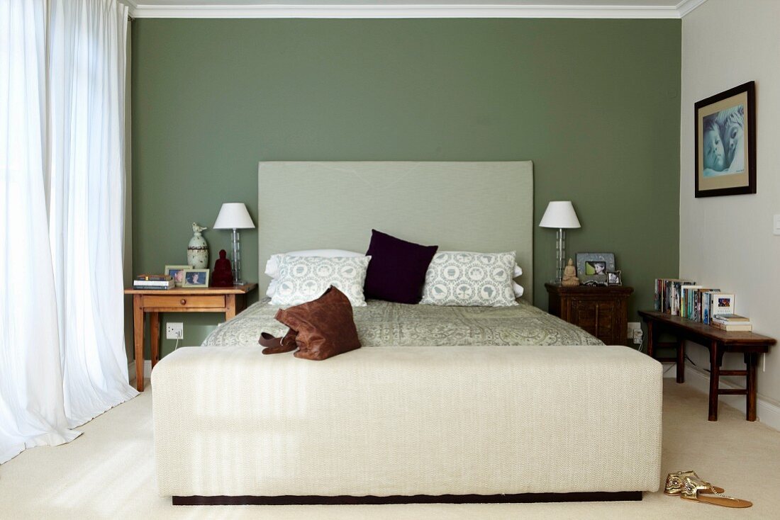 Simple bed with headboard against green-painted wall in classic bedroom