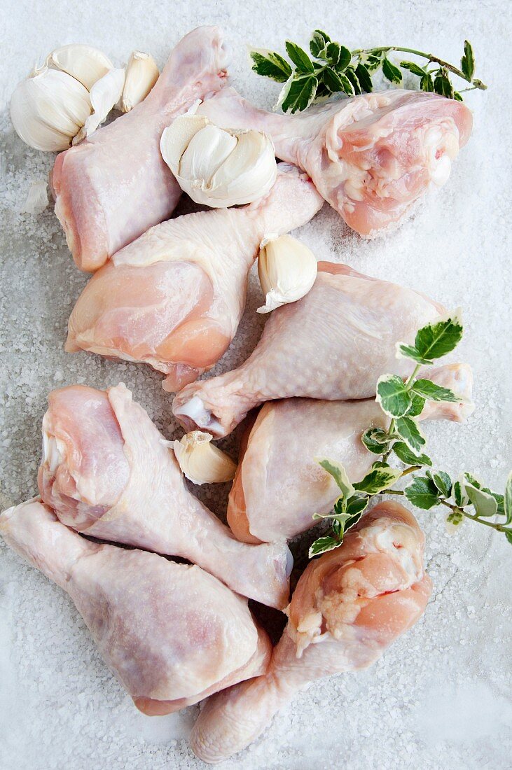 Raw chicken drumsticks with garlic (view from above)