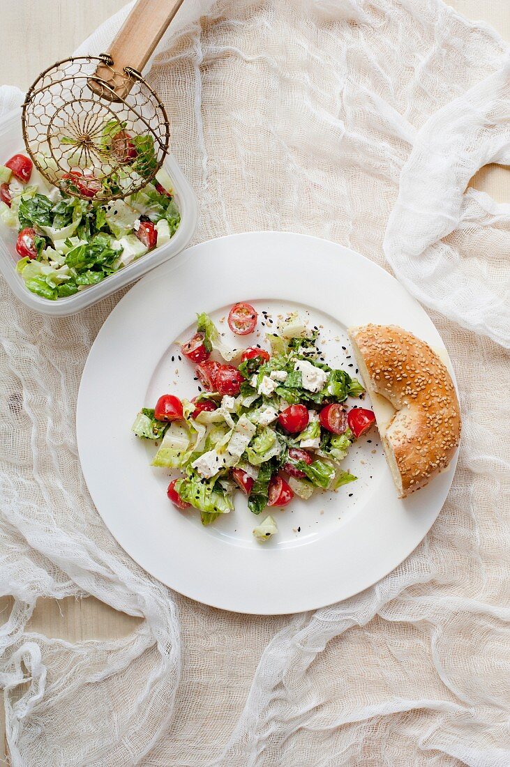 Leaf salad with tomatoes, feta and fresh bread (view from above)