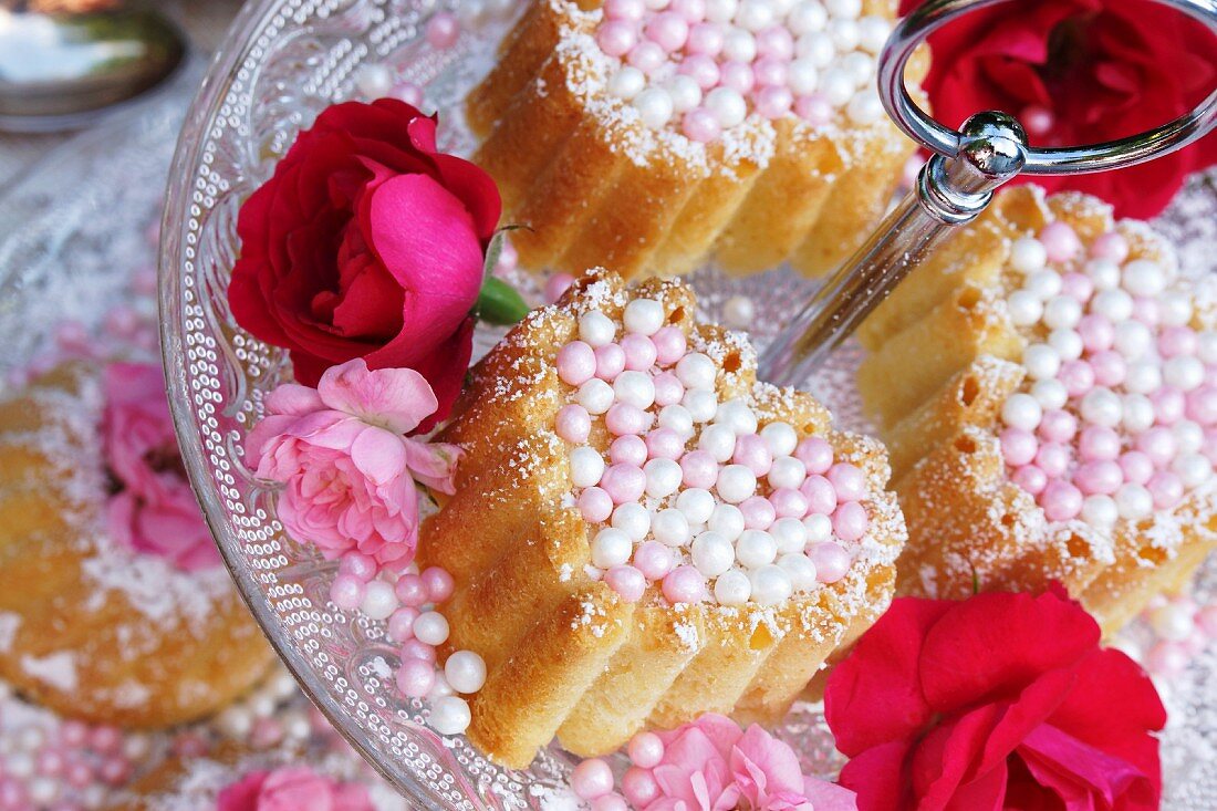 Small Bundt cakes with sugar pearls and flower decoration on a tiered cake stand