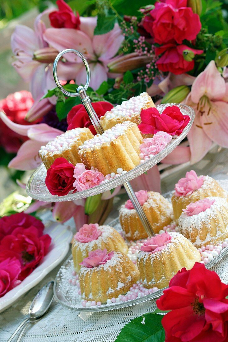 Kleine Napfkuchen mit Zuckerperlen und Rosendeko auf Etagere