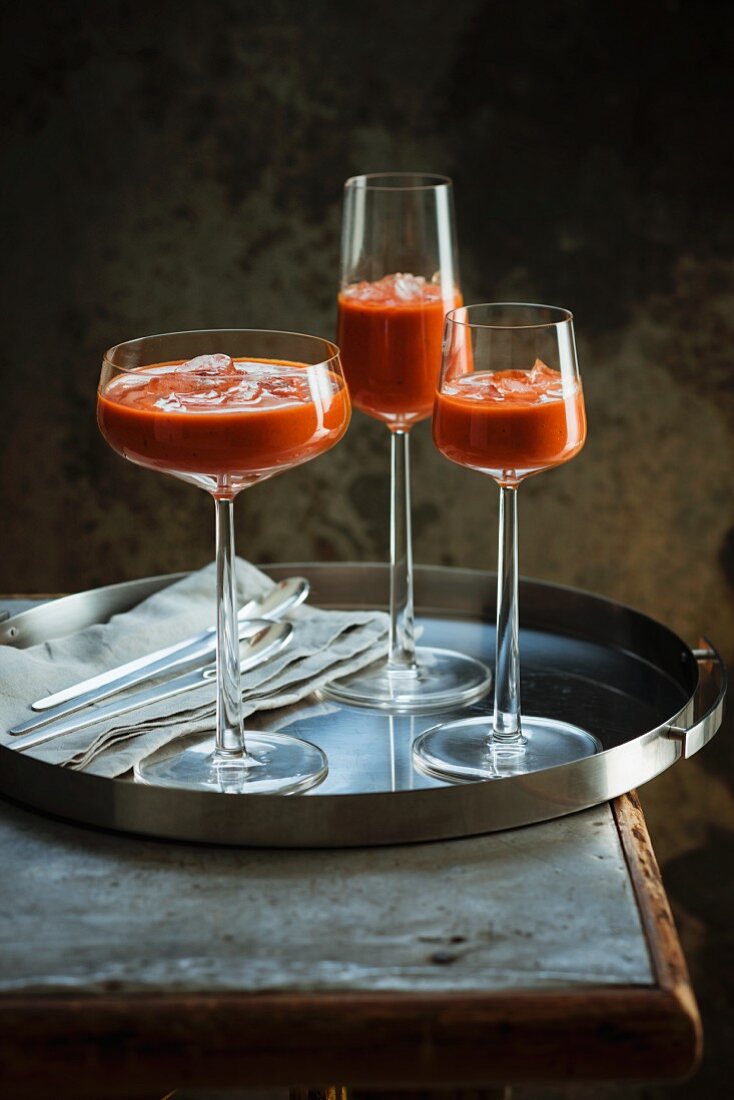 Gazpacho with ice served in stemmed glasses on a tray