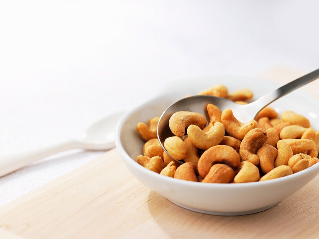 Toasted cashew nuts in a small bowl with a spoon
