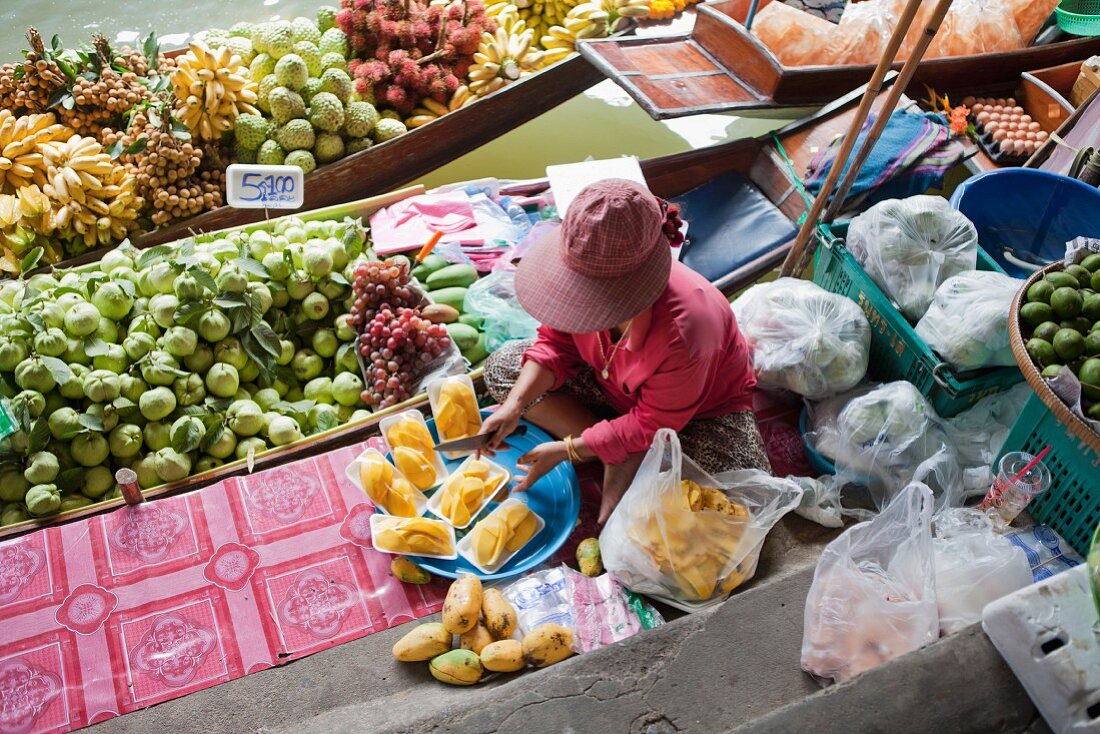 Frau verkauft Früchte auf dem Boot am Markt (Bangkok, Thailand)