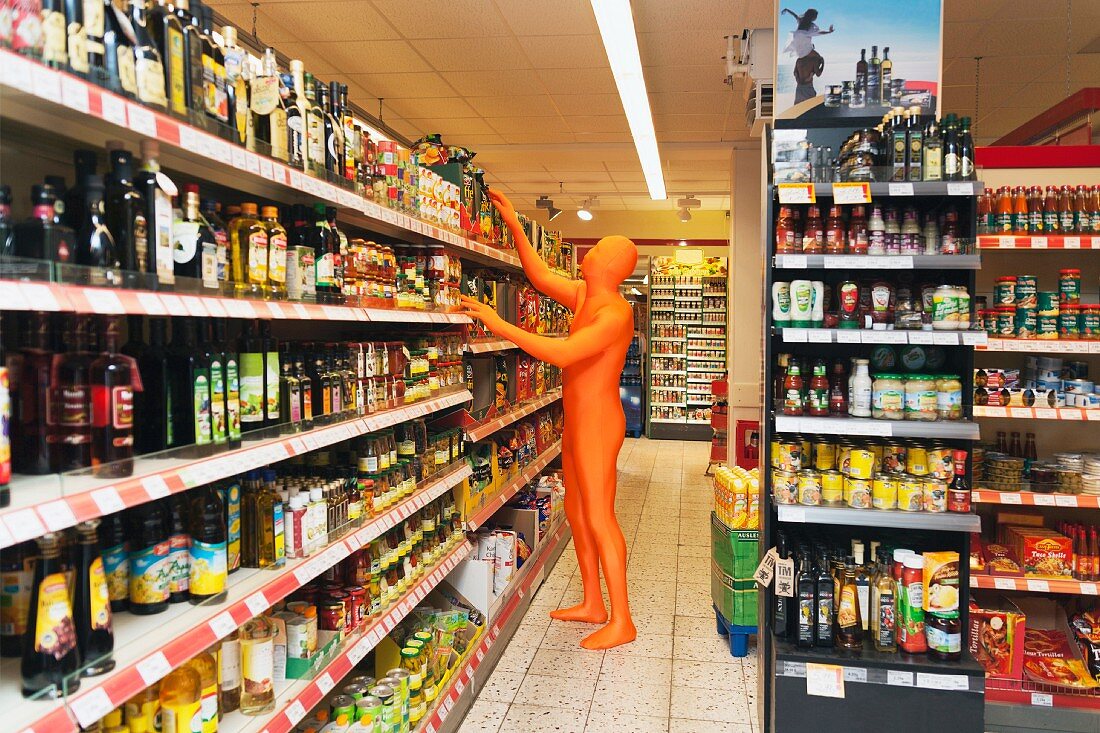 A man in an orange costume looking at products in a supermarket