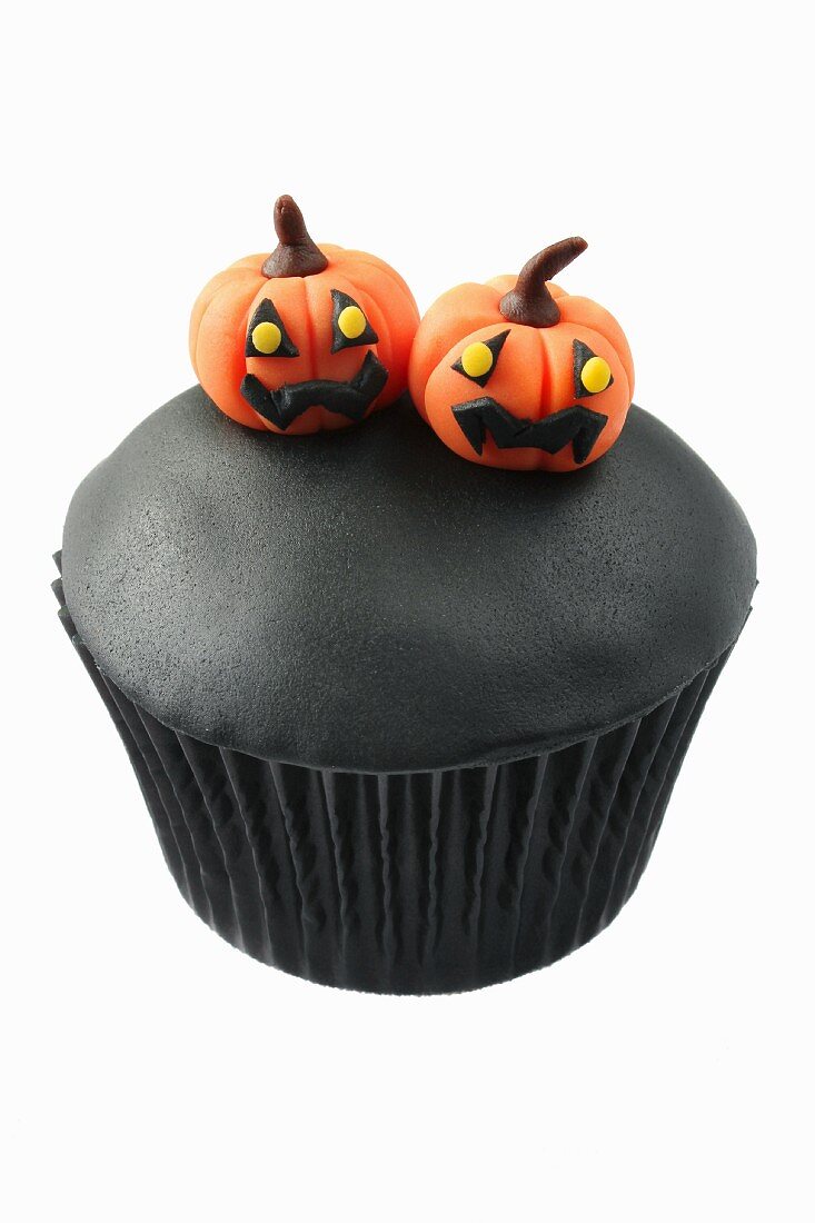 A black muffin decorated with marzipan pumpkins