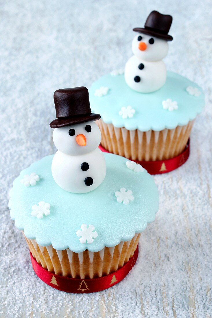 Two wintry cupcakes decorated with snowmen