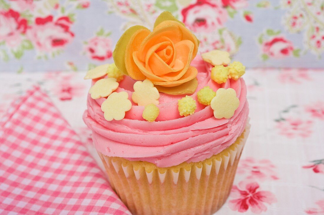 Rosa Cupcake verziert mit Zuckerrose und Süssigkeiten