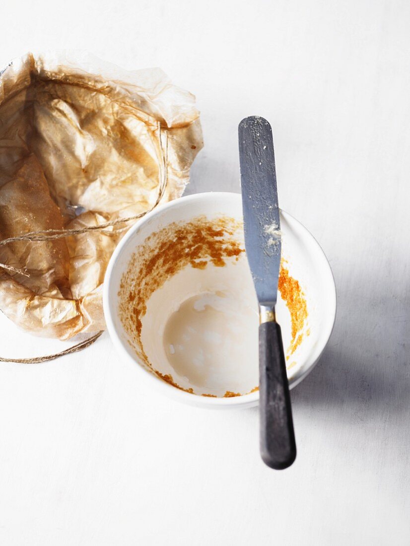 Baking paper and ramekin with remains of a sponge pudding