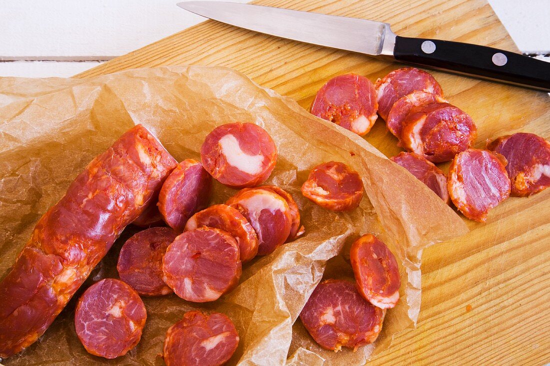 Chorizo, cut into slices with a sharp knife on a wooden chopping board