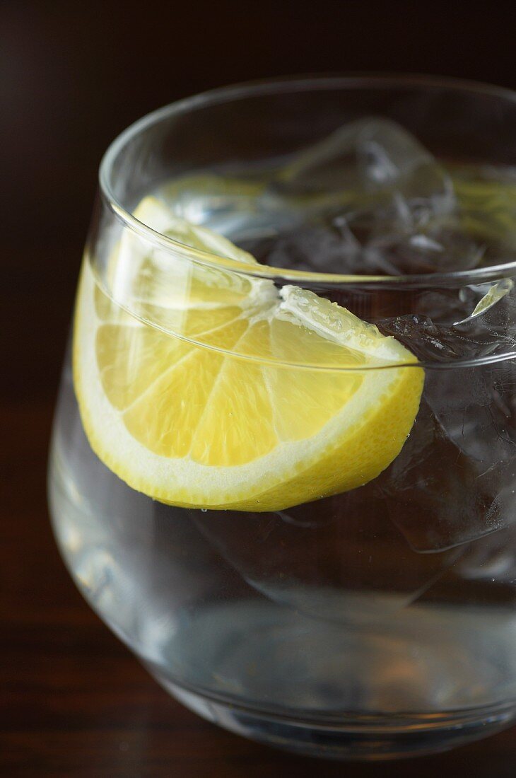 A glass of water with a wedge of lemon and ice cubes