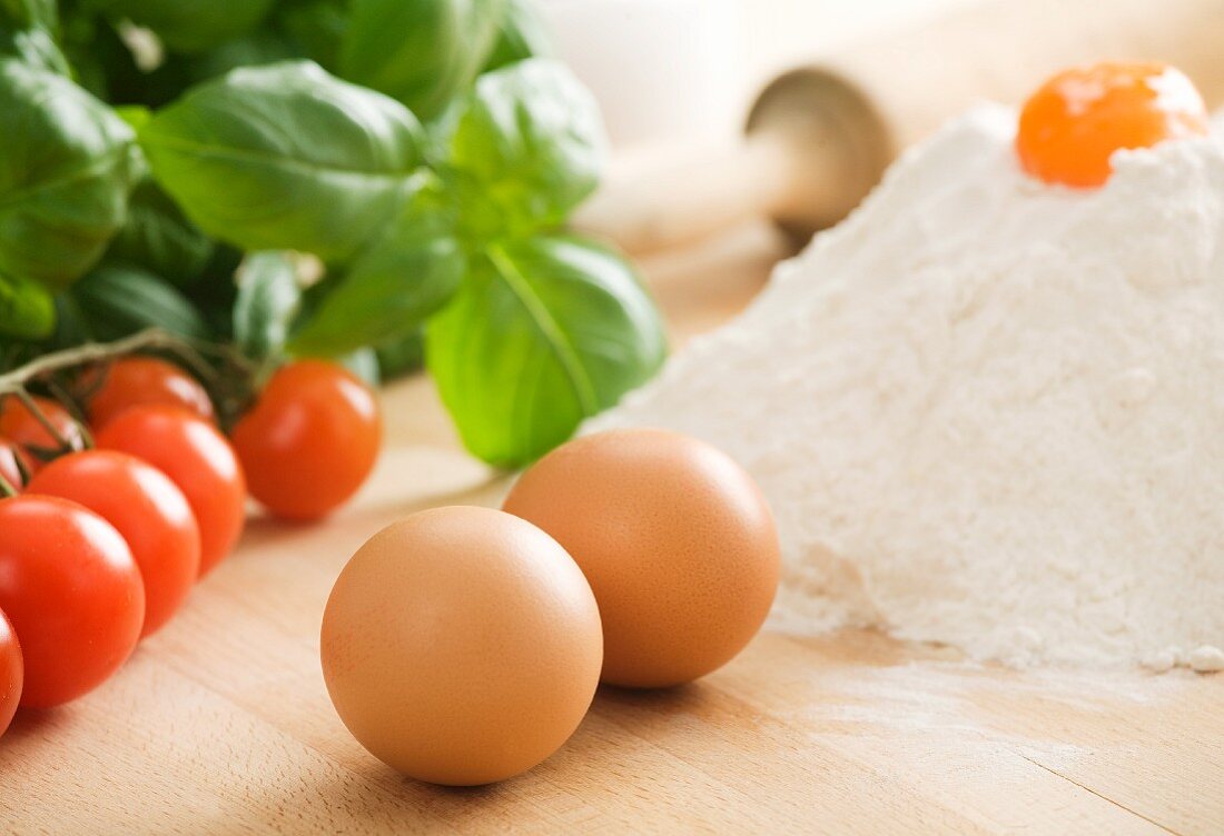 Eggs, flour, cherry tomatoes, basil and a rolling pin