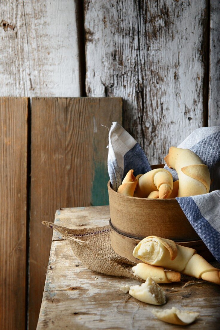Croissants in a wooden basket on a rustic wooden table