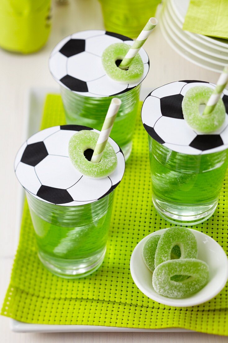 Football-shaped paper glass covers with straws and jelly sweets