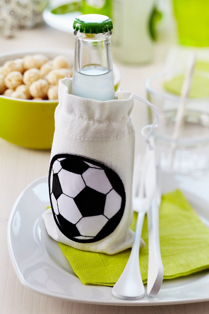 A lemonade bottle in a small fabric bag with a football decoration