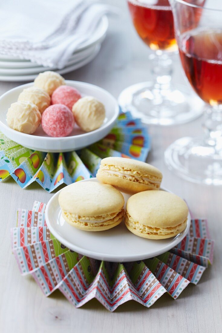 Bunte Papierrosette als Untersetzer für kleine Teller mit Vanille-Macarons und Pralinen
