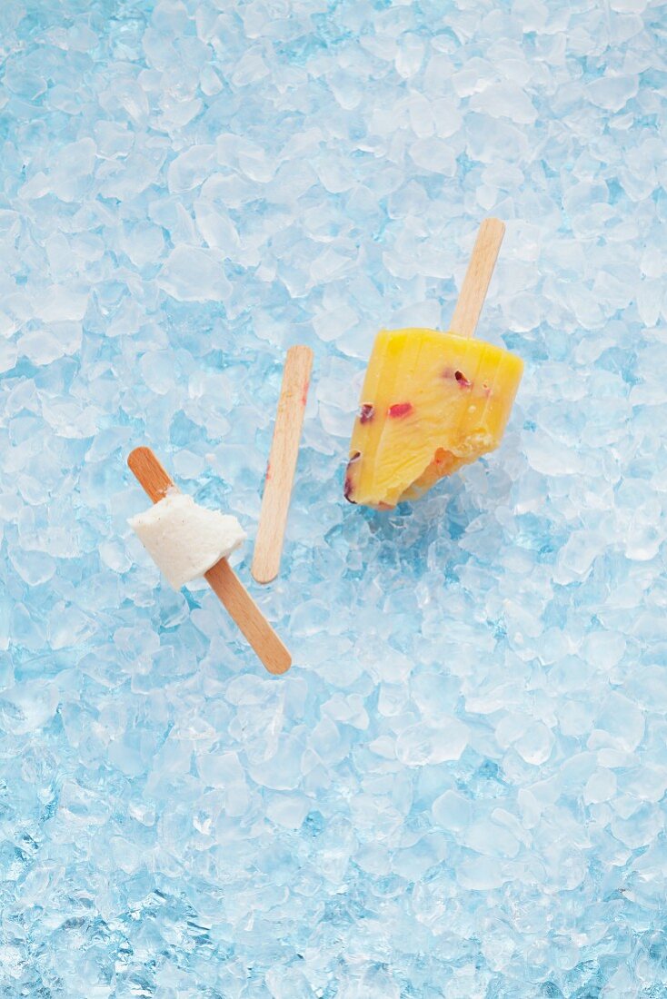 Home-made fruit ice lollies on crushed ice, eaten and part eaten