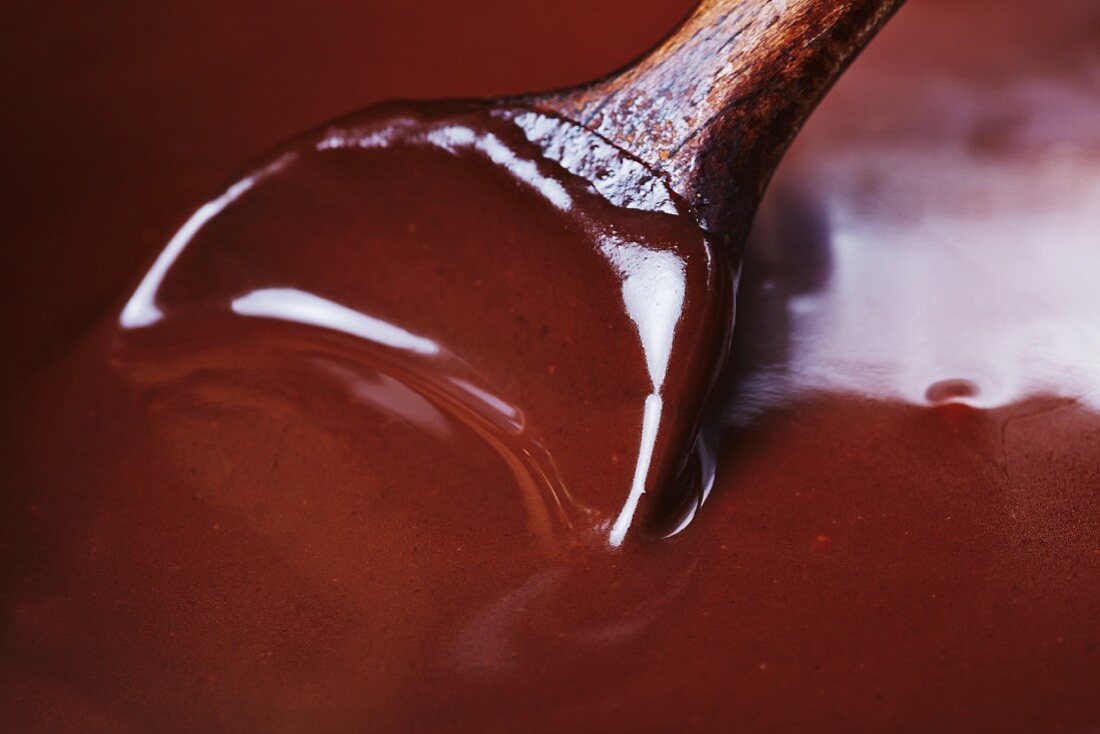 A wooden spoon stirring melted dark chocolates