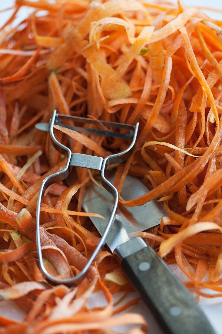 Carrot peelings, a peeler and a knife