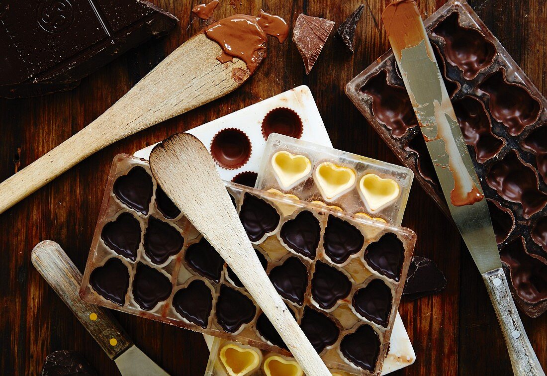 Verschiedene Gussformen für Schokoladenpralinen, Messer und Kochlöffel