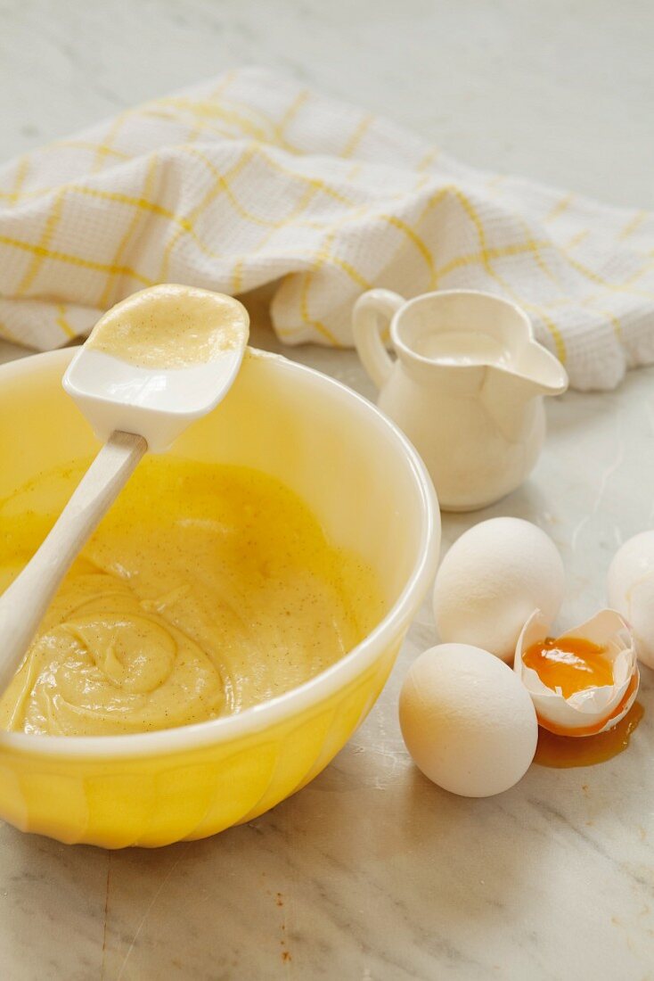 A bowl of cake mix next to eggs, one cracked open