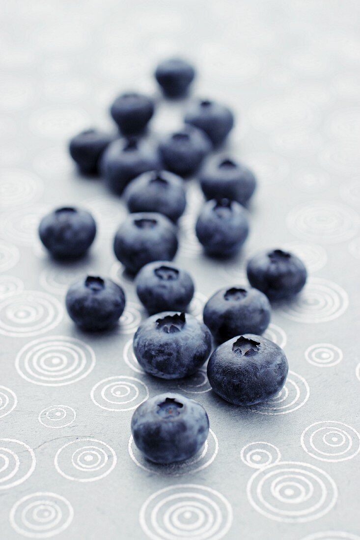 Fresh blueberries lying on a patterned tablecloth (close-up)