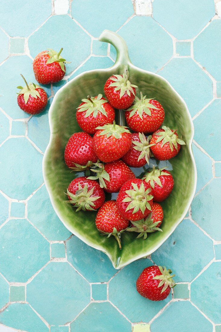 Fresh strawberries in a green, leaf-shaped bowl (view from above)