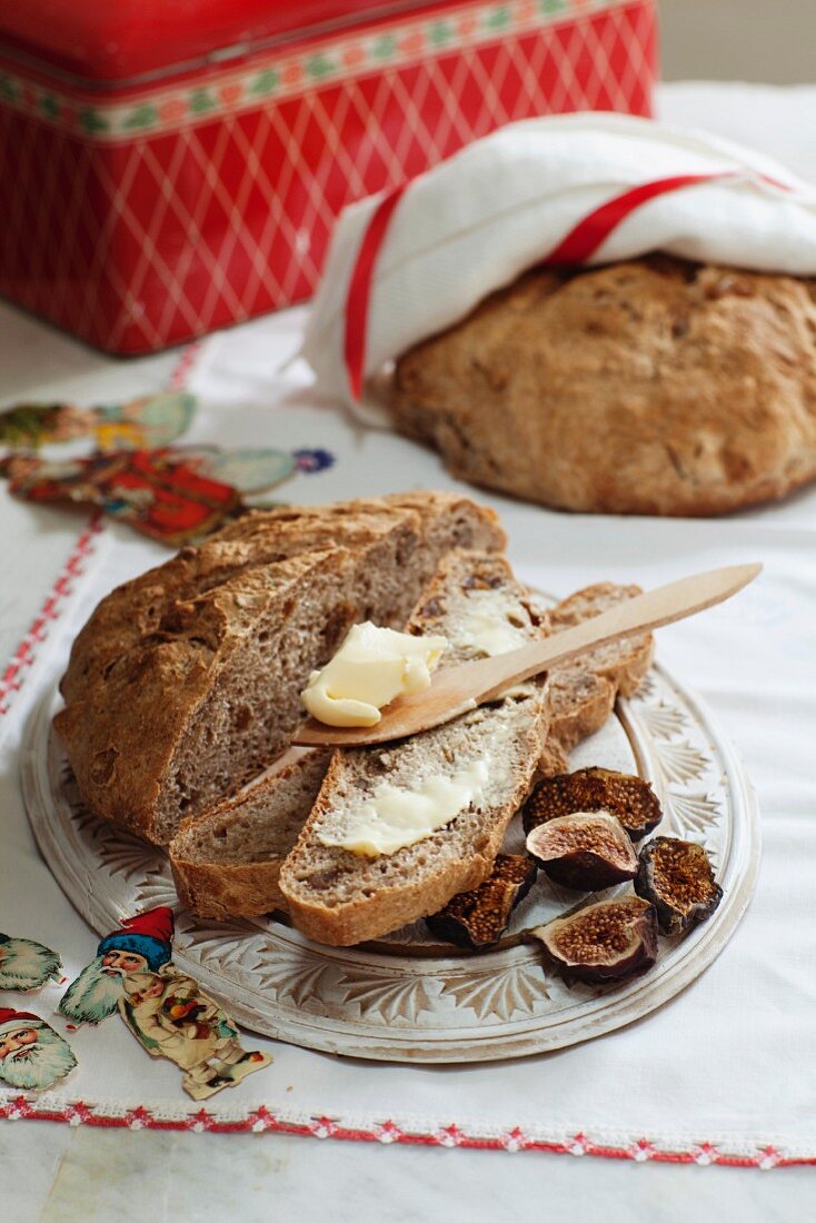 Spelt bread with walnuts and dried figs with a slice spread with butter