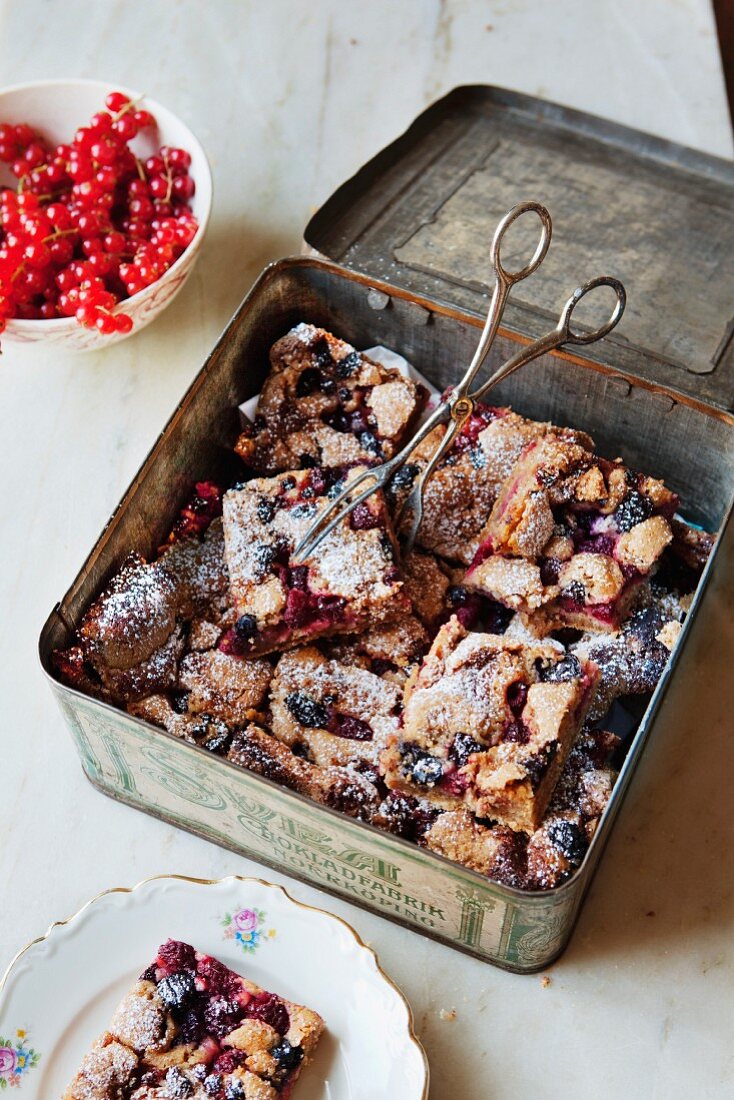 Cinnamon cake with mixed berries, slices in a tin box and on a plate