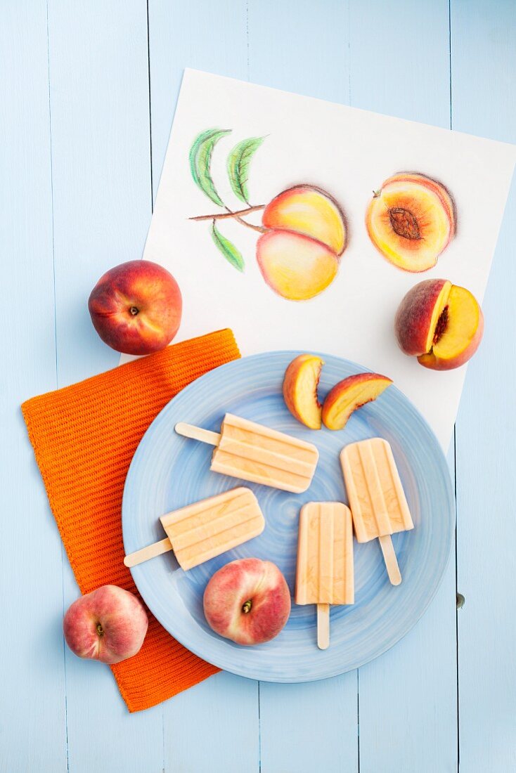 Peach and yoghurt ice lollies and fresh peaches with a drawing of peaches