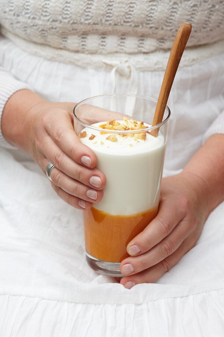 A woman holding a glass of apricot dessert