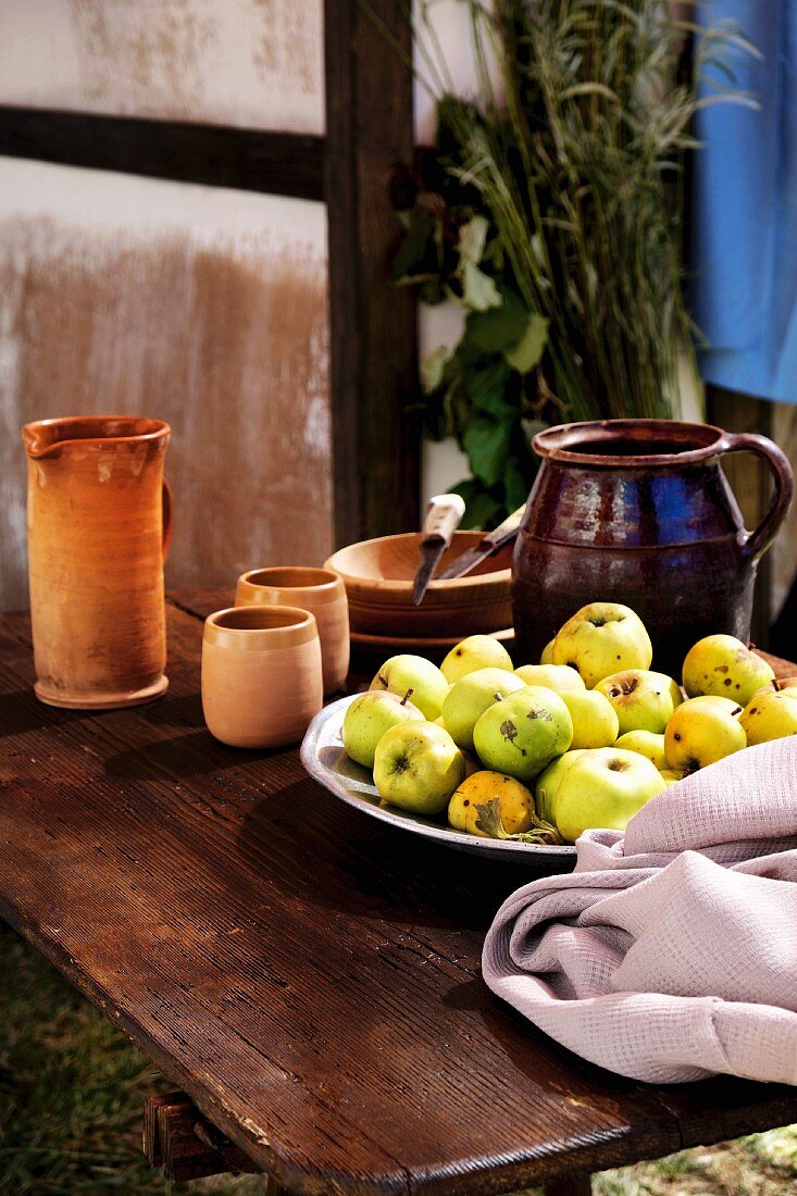 Stillleben mit Tongeschirr & Schale mit Äpfeln auf Holztisch
